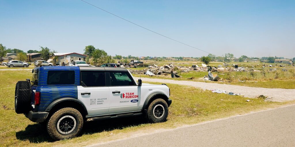 Ford bronco in front of tornado damage.